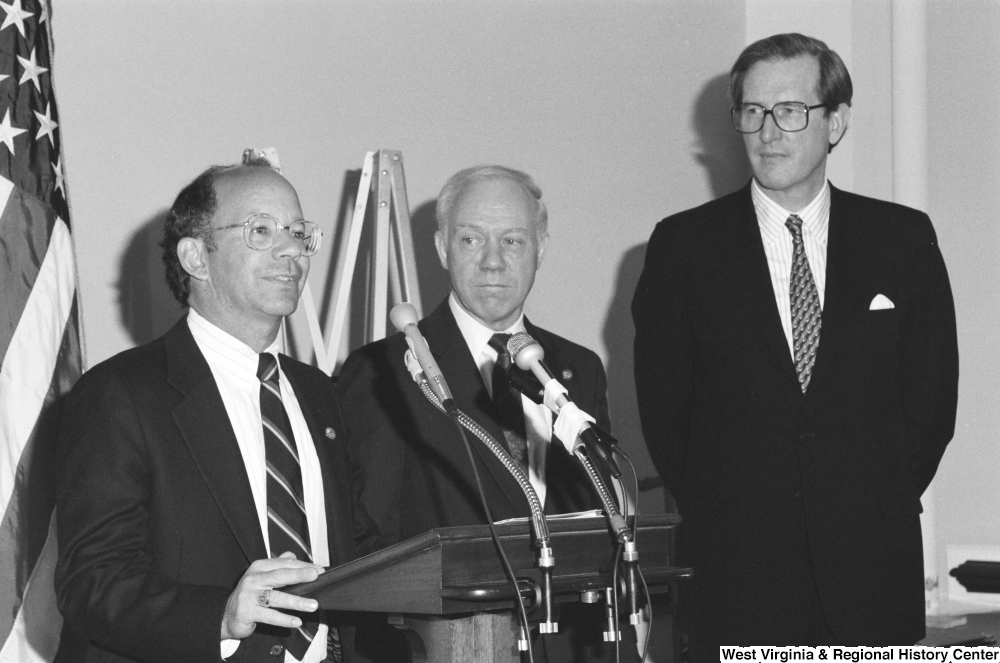["Senator John D. (Jay) Rockefeller stands next to two unidentified men at a press event."]%