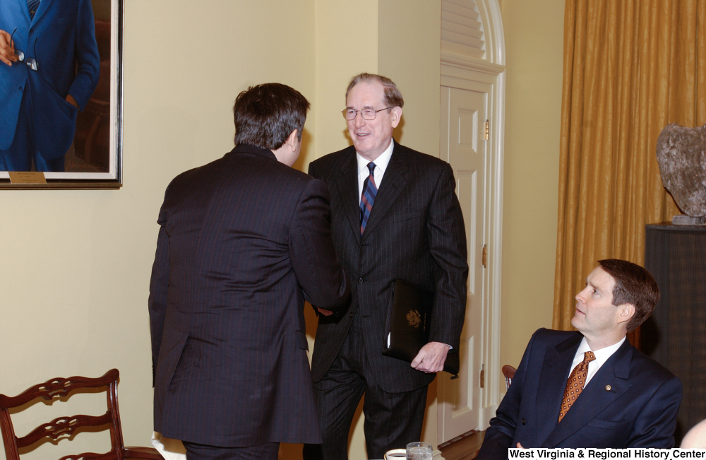 ["Senator John D. (Jay) Rockefeller shakes hands with an unidentified man at a lunch event at the Senate."]%