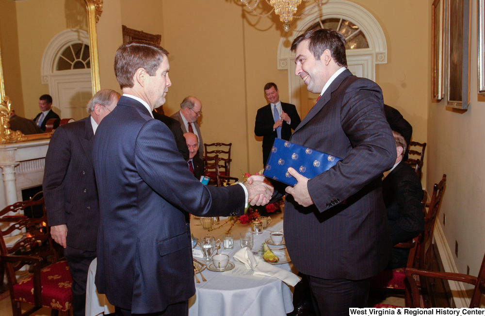 ["Two men shake hands after a luncheon at the Senate."]%