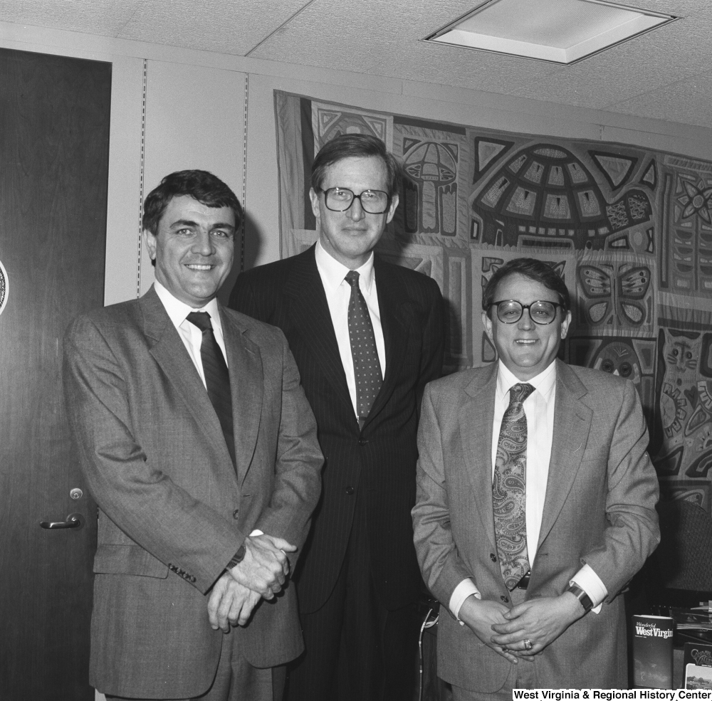 ["Senator John D. (Jay) Rockefeller stands between two unidentified men in his office."]%