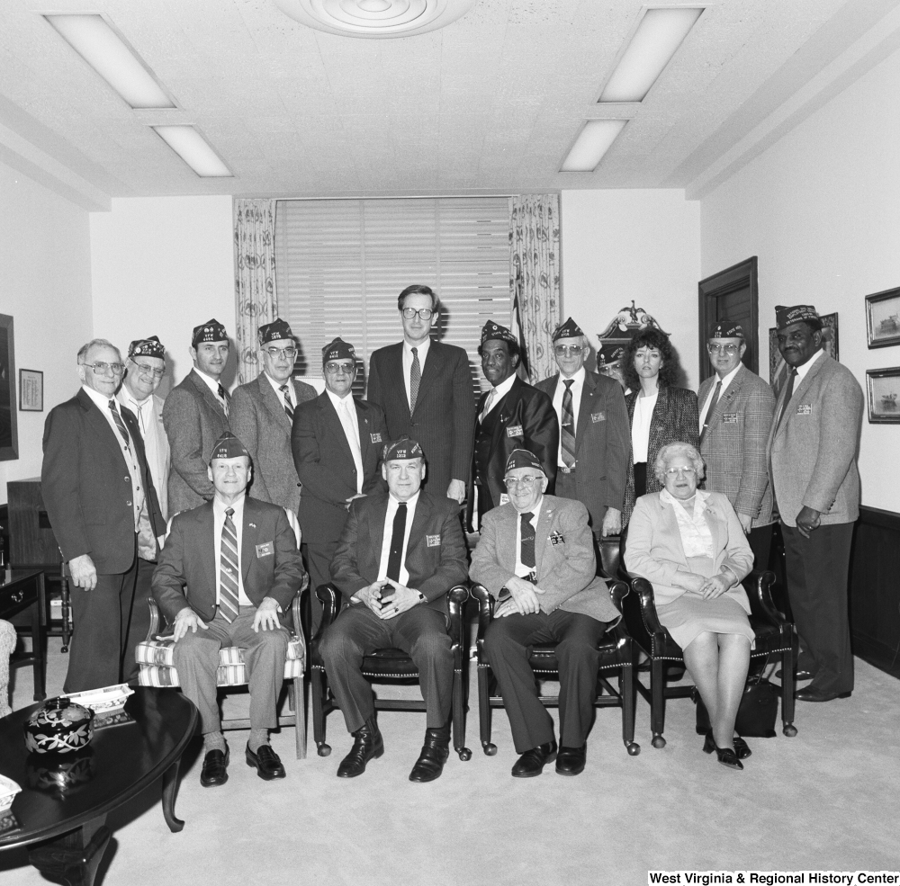 ["Senator John D. (Jay) Rockefeller stands in the center of a large group of Veterans of Foreign Wars members who are visiting his office."]%