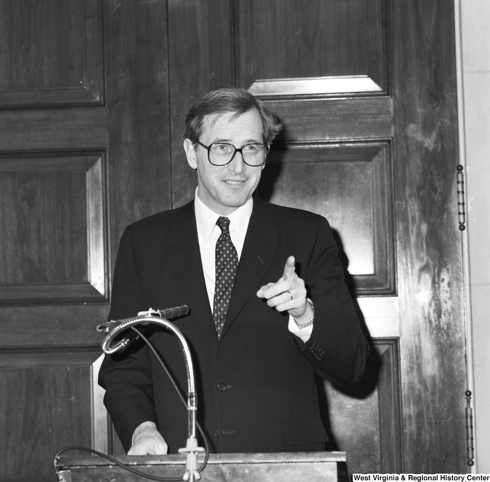 ["Senator John D. (Jay) Rockefeller smiles and points towards the audience as he speaks at an unknown event in Washington."]%