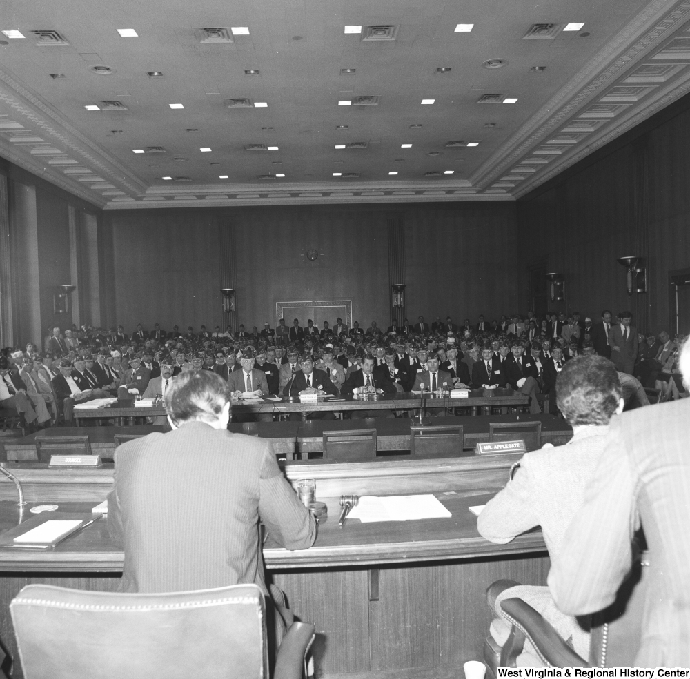 ["This photograph shows the audience at a committee hearing at the Senate. This appears to be a Veterans Affairs committee hearing and there are a large number of American Legion members in the audience."]%