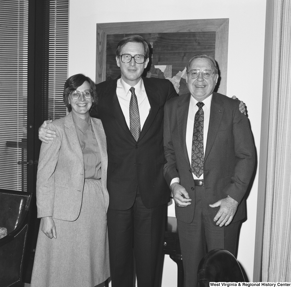 ["Senator John D. (Jay) Rockefeller stands between two unidentified individuals in his office."]%