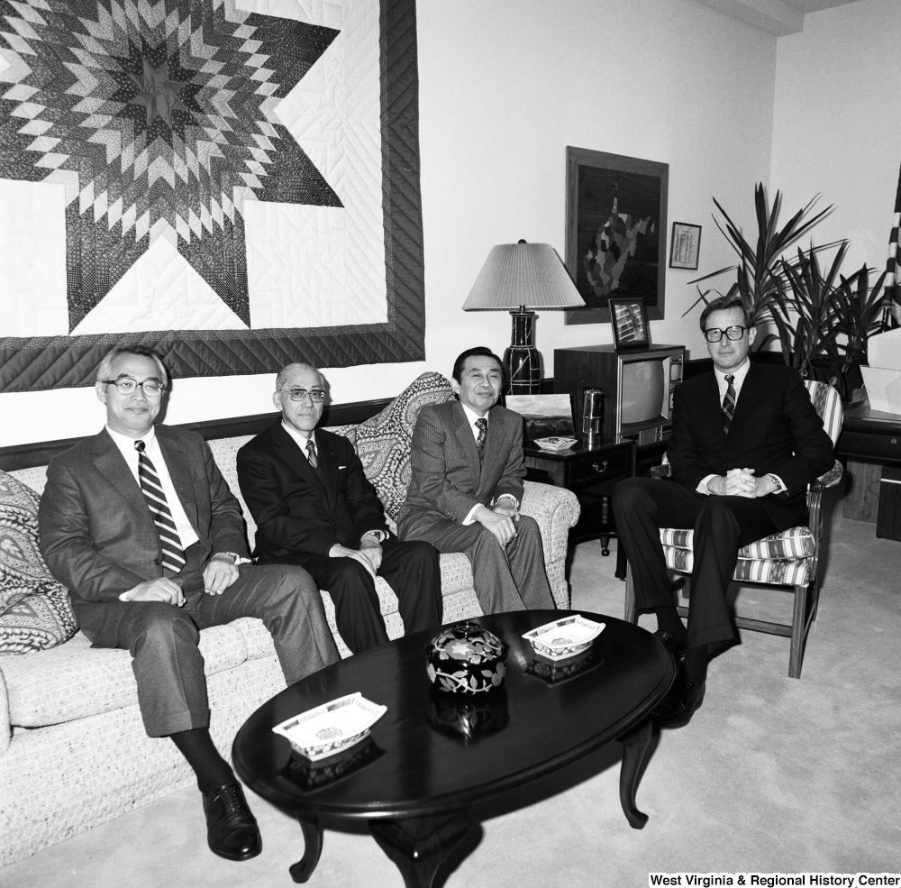 ["Senator John D. (Jay) Rockefeller sits in a chair in his office with a group of unidentified individuals."]%
