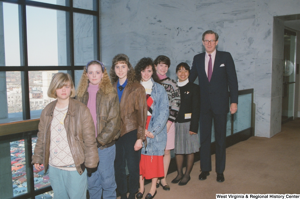 ["Senator John D. (Jay) Rockefeller stands with a group of girls in the hallway of the Hart Building."]%