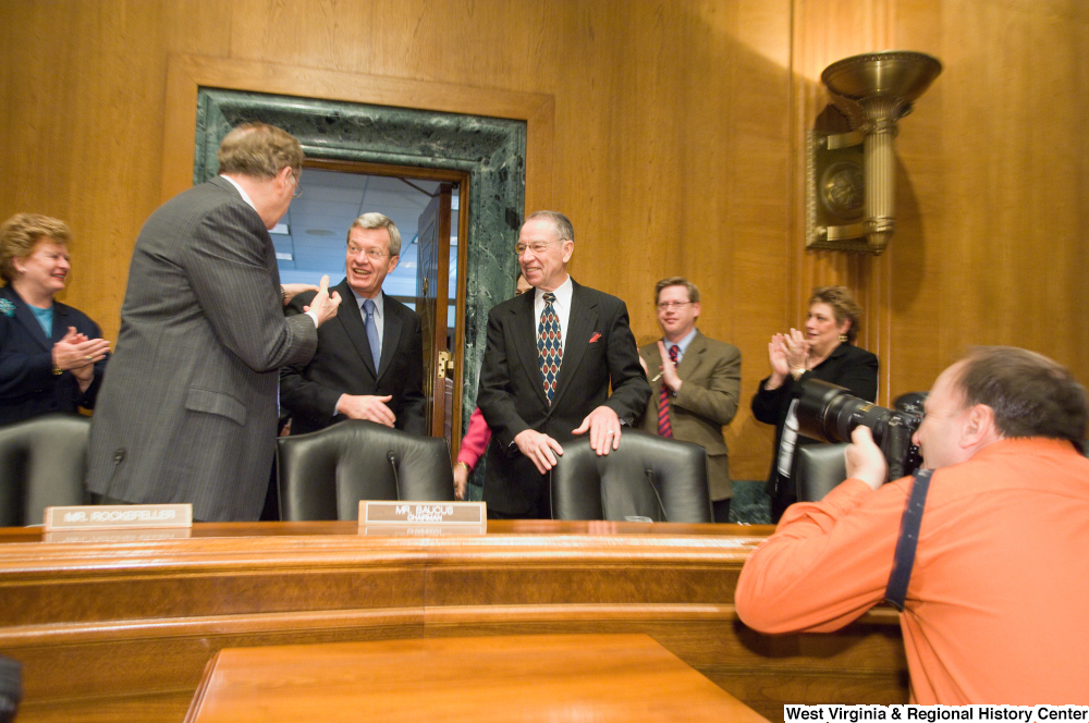 ["A group of Senators greet Senator Max Baucus as he enters the Senate Finance Committee hearing room."]%