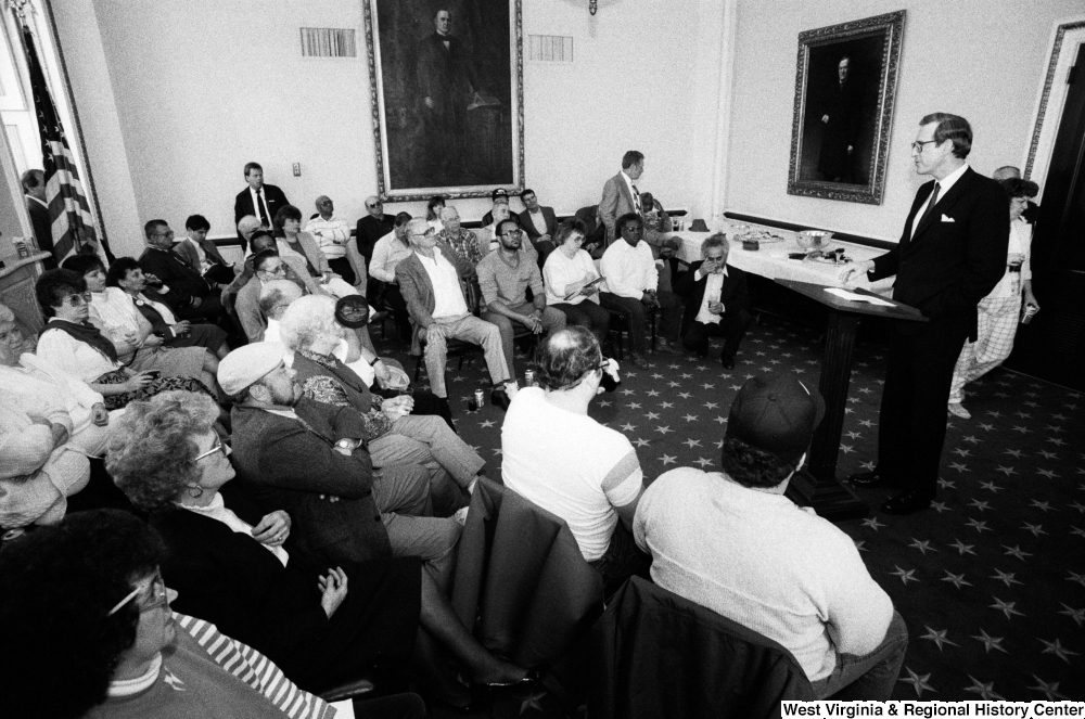 ["Senator John D. (Jay) Rockefeller speaks about black lung disease in West Virginia with a group in a room in the Senate."]%
