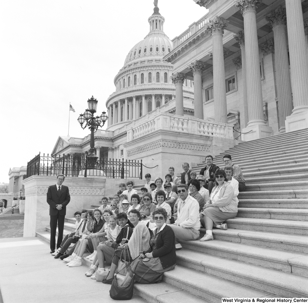 ["Senator John D. (Jay) Rockefeller stands for a photograph with a large unidentified group that sits on the steps of the Capitol Building."]%