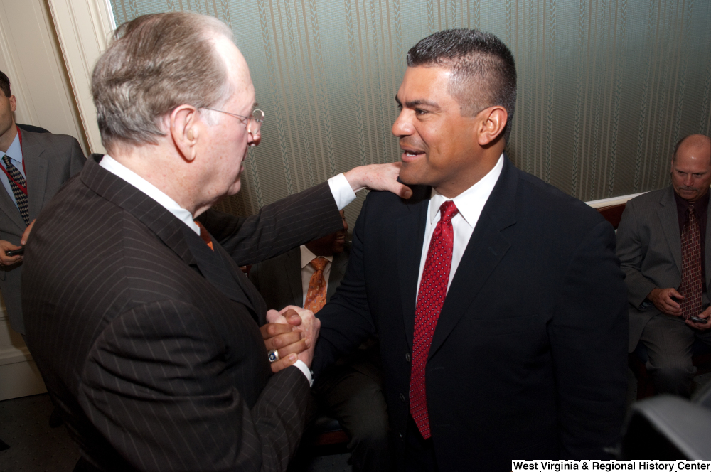 ["Senator John D. (Jay) Rockefeller shakes hands with an unidentified man at an event to honor Bobby Cox."]%