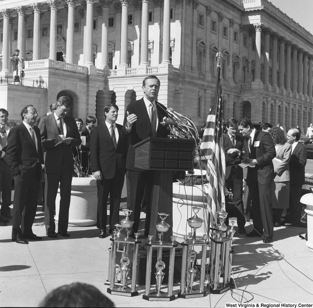 ["An unidentified man speaks to the crowd at a clean vehicle event outside the Senate."]%