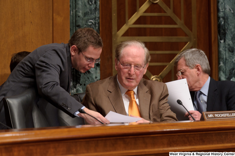 ["Senator John D. (Jay) Rockefeller receives a sheet of paper from an aide during a Finance Committee hearing."]%
