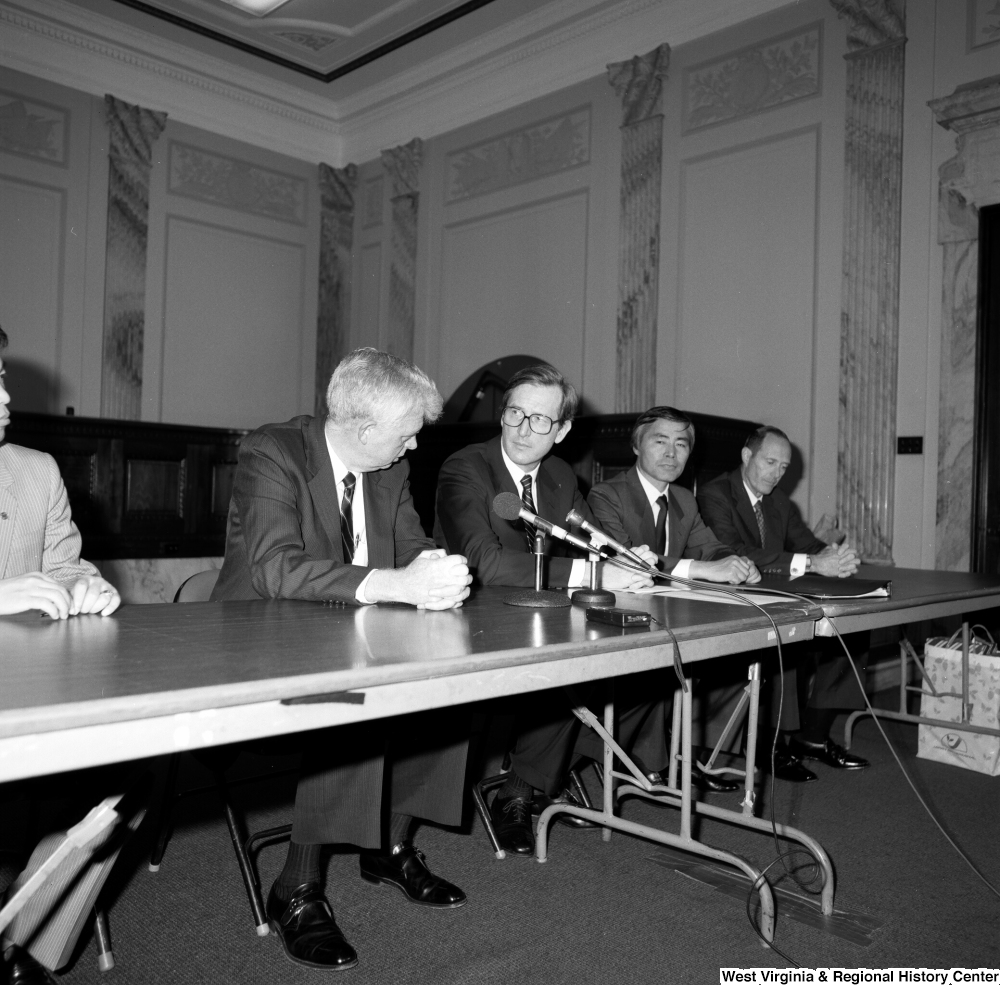["Senator John D. (Jay) Rockefeller sits behind a table at a press event."]%