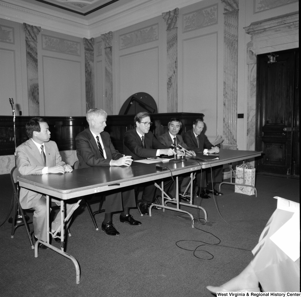 ["Senator John D. (Jay) Rockefeller sits behind a table at a press event in the Senate."]%
