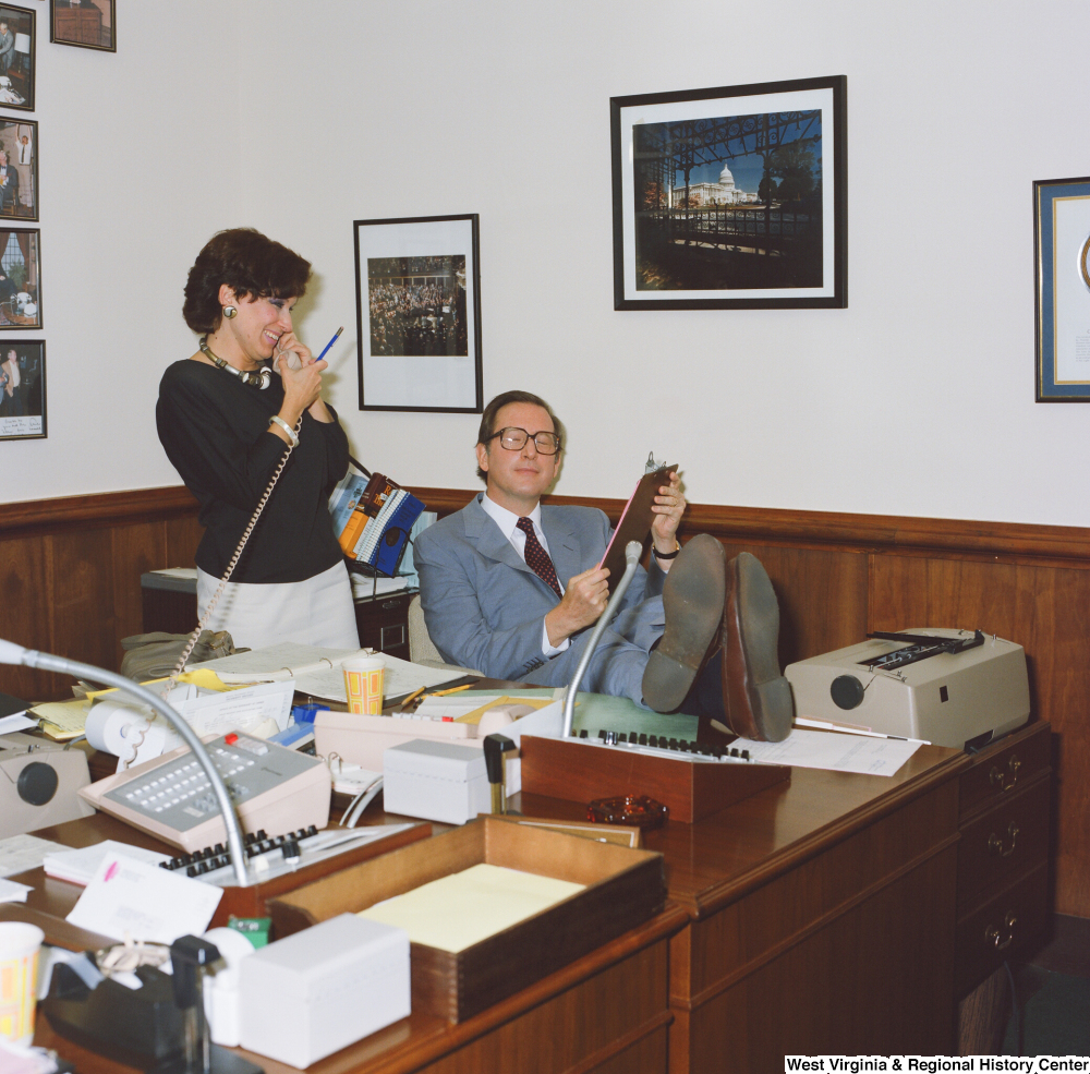 ["Senator John D. (Jay) Rockefeller props his legs up on a desk and speaks to an unidentified staff member in his Washington office."]%