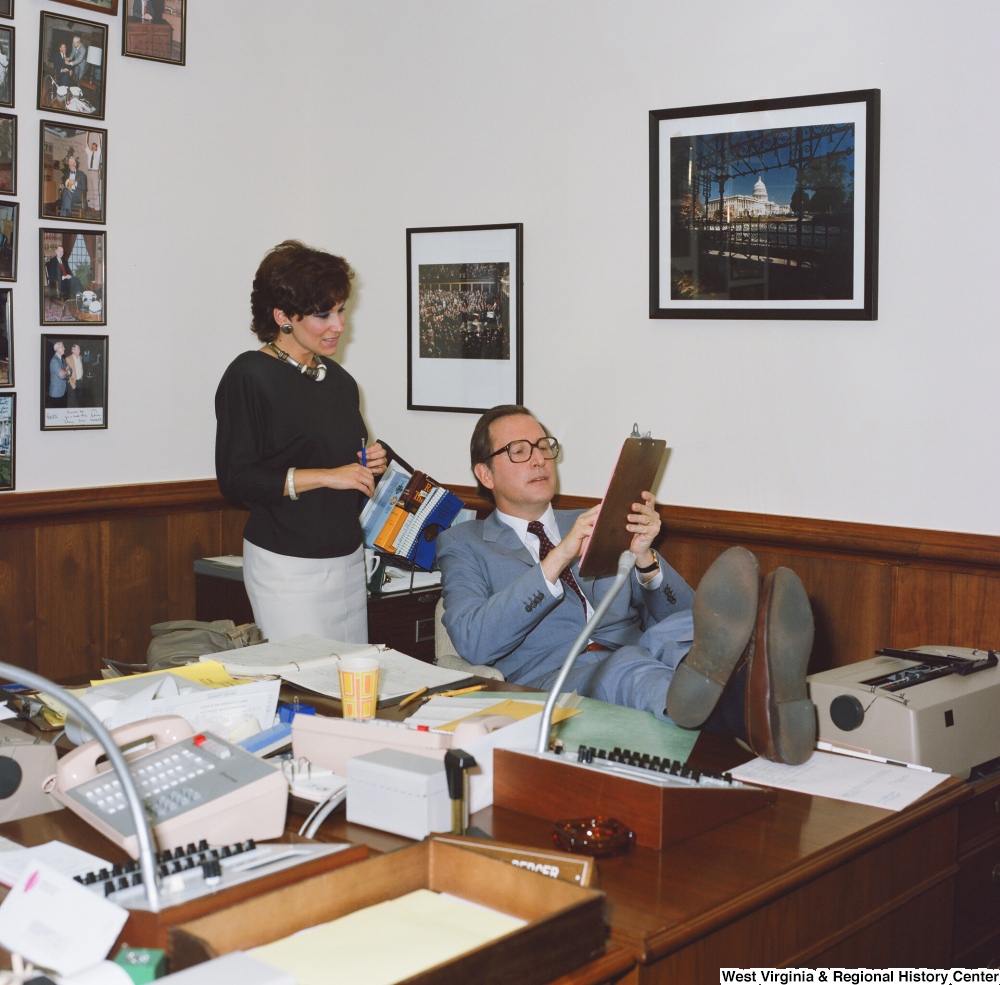 ["Senator John D. (Jay) Rockefeller points out something on a clipboard in a discussion with an unidentified staff member."]%