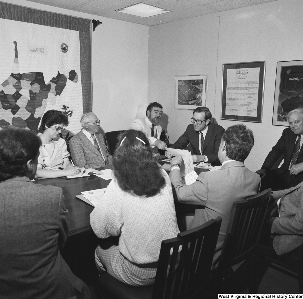 ["Senator John D. (Jay) Rockefeller looks at a document as he sits around a conference table at a planning meeting for the Blackwater Canyon Railroad project."]%