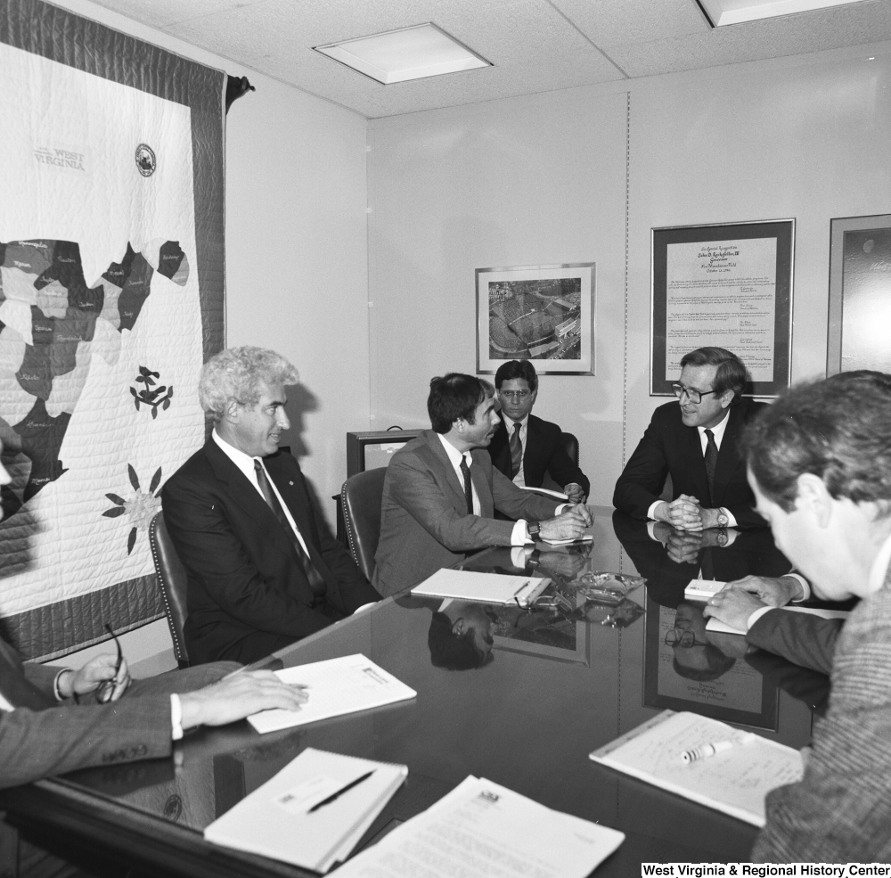 ["Senator John D. (Jay) Rockefeller sits at a conference table in his office with several unidentified men."]%