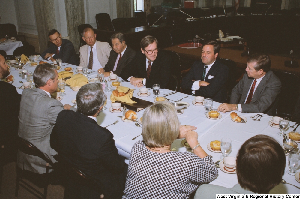 ["Senator John D. (Jay) Rockefeller listens as an unidentified guest speaks during a reception event for American Electric Power."]%