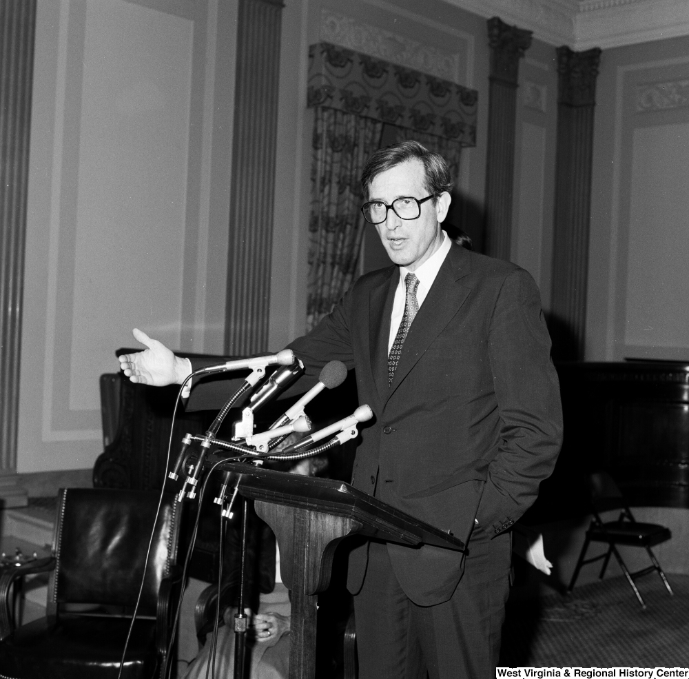 ["Senator John D. (Jay) Rockefeller speaks with an arm outstretched at one of the Senate buildings."]%