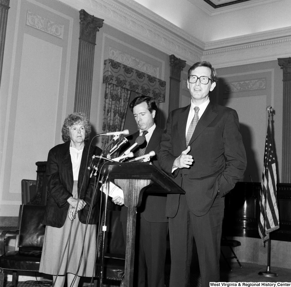 ["Senator John D. (Jay) Rockefeller speaks about the Dislocated Workers Improvement Act of 1987 while Senator John Heinz and an unidentified woman stand next to him."]%