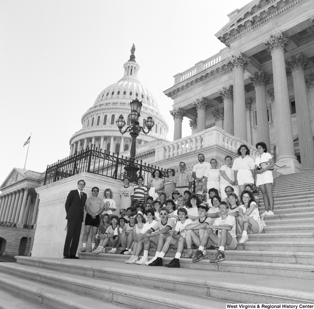 ["Senator John D. (Jay) Rockefeller stands for a photograph with a seated group of students on the steps of the US Capitol."]%