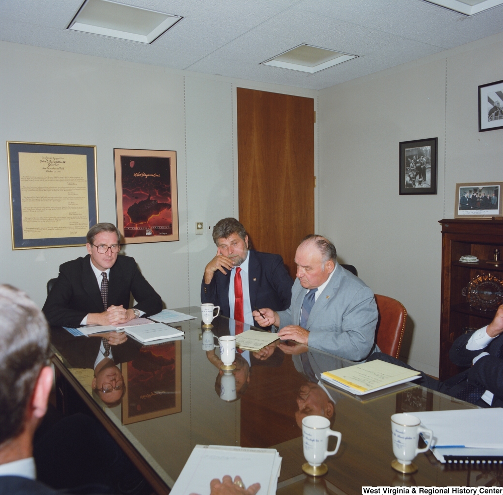 ["Senator John D. (Jay) Rockefeller listens to another man speak during a meeting in his office."]%