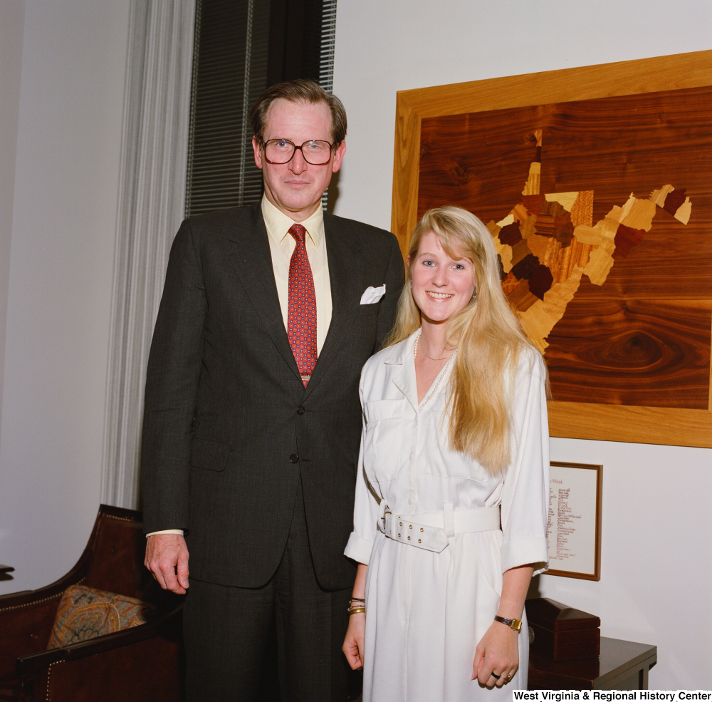 ["Senator John D. (Jay) Rockefeller stands next to an intern in his office."]%