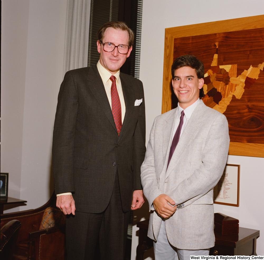 ["An intern stands beside Senator John D. (Jay) Rockefeller in his office."]%