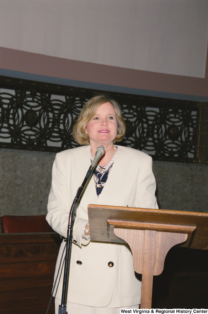 ["Sharon Rockefeller stands behind a lectern and microphone."]%