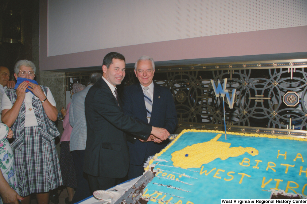 ["Senator Robert C. Byrd and another man cut a huge cake in celebration of West Virginia's birthday."]%