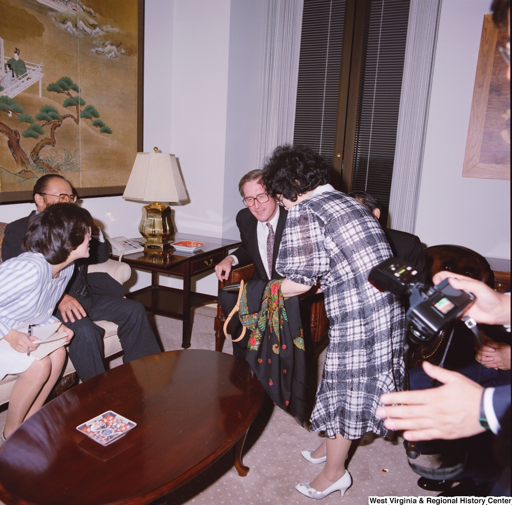 ["Senator John D. (Jay) Rockefeller looks at fabric that a woman is showing him during a meeting with representatives from the Japanese Embassy."]%