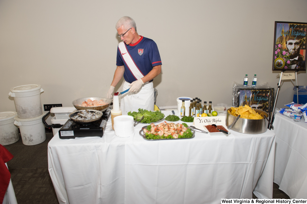 ["A man cooks shrimp at the 150th birthday celebration for West Virginia."]%