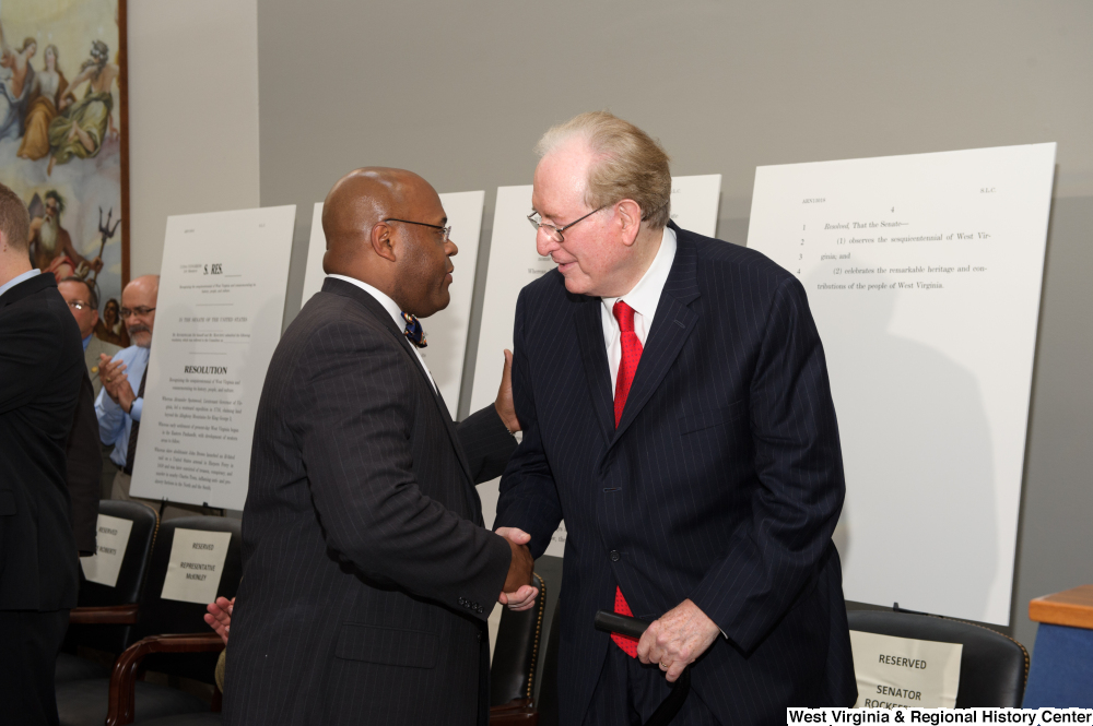 ["Senator John D. (Jay) Rockefeller shakes hands with a man at a West Virginia Day celebration."]%