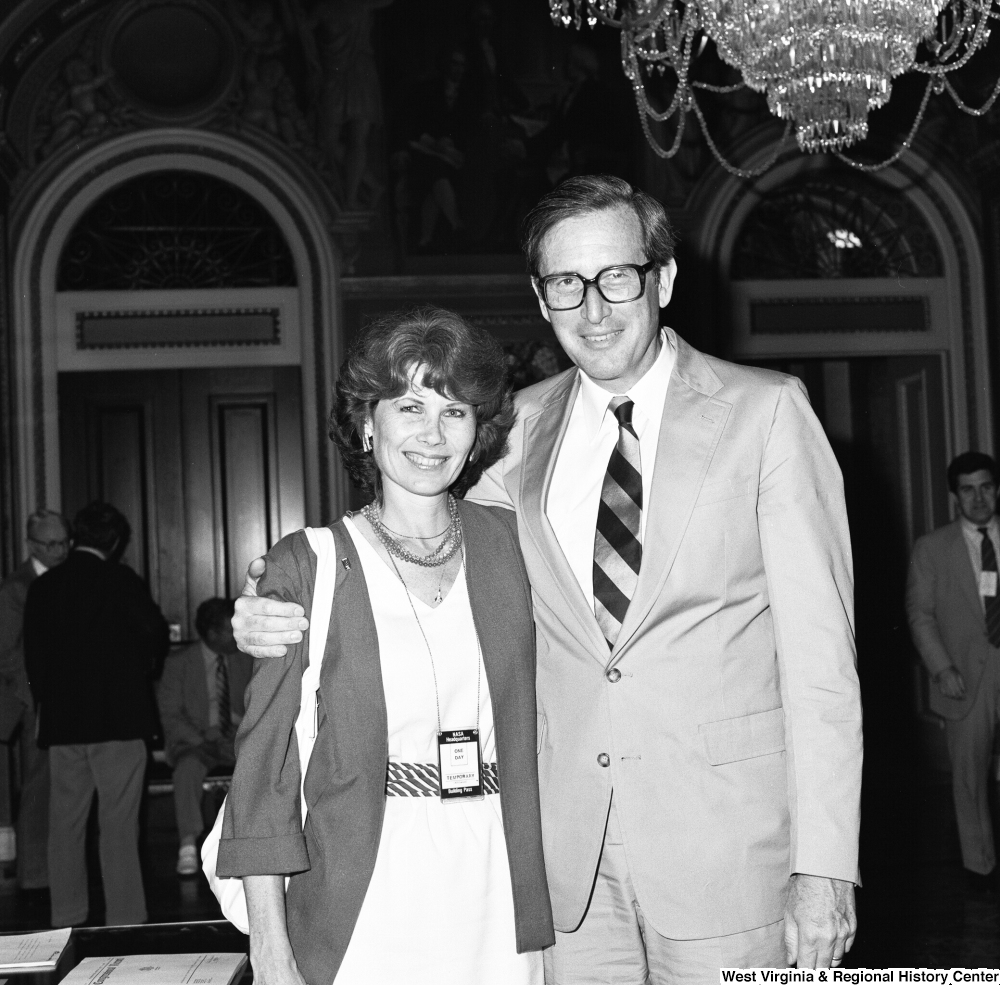 ["Senator John D. (Jay) Rockefeller poses for a photograph in the Senate with an unidentified woman wearing a \"NASA Headquarters\" badge."]%