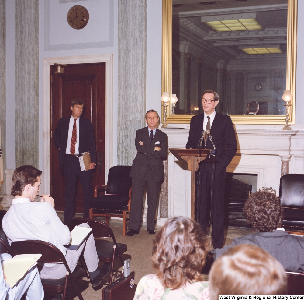["This color photograph shows Senator John D. (Jay) Rockefeller speaking in front of an audience at an event in a Senate building."]%