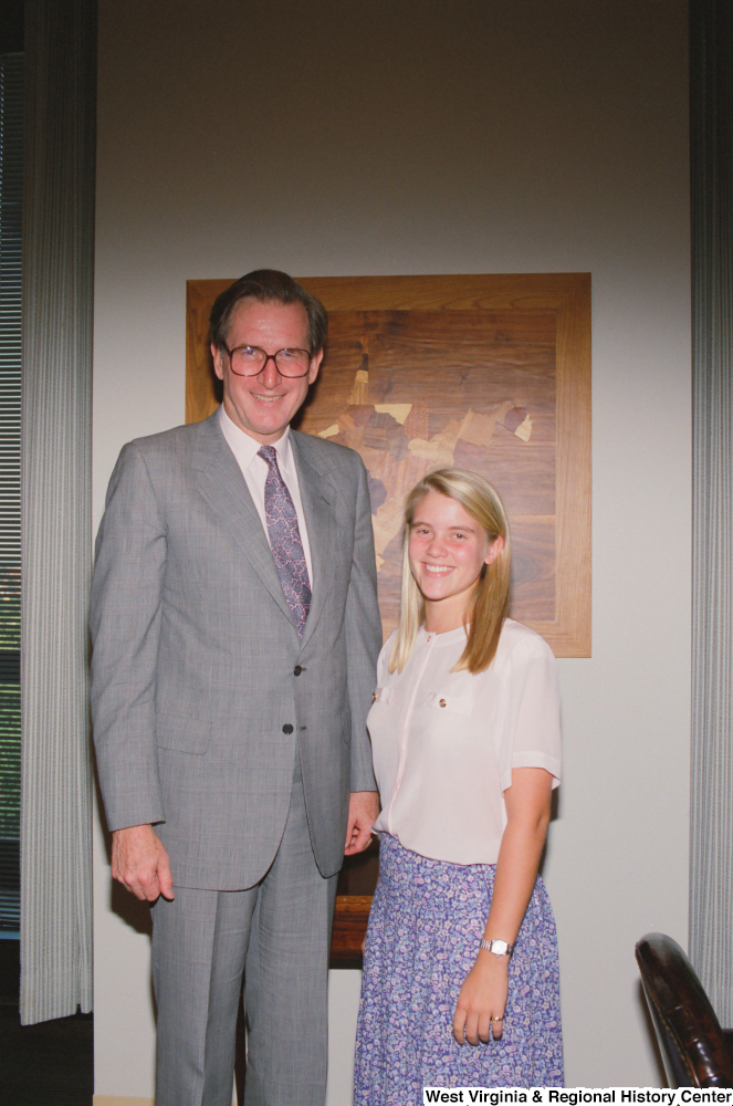 ["Senator John D. (Jay) Rockefeller stands next to a young woman who appears to be an intern."]%