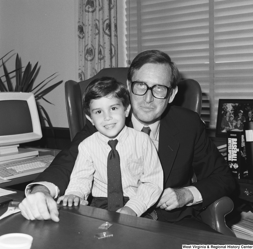 ["An unidentified boy sits on Senator John D. (Jay) Rockefeller's lap behind the desk in his office."]%