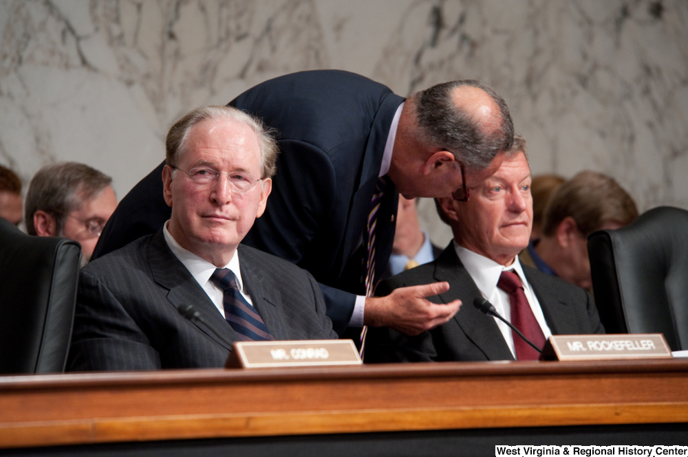 ["Senator Max Baucus is briefed by an adviser during a Finance Committee hearing about health care reform."]%