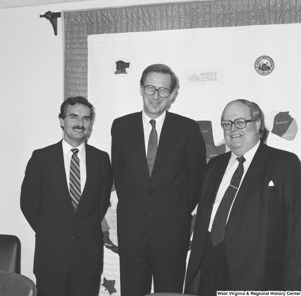 ["Senator John D. (Jay) Rockefeller stands between two unidentified men in his office."]%