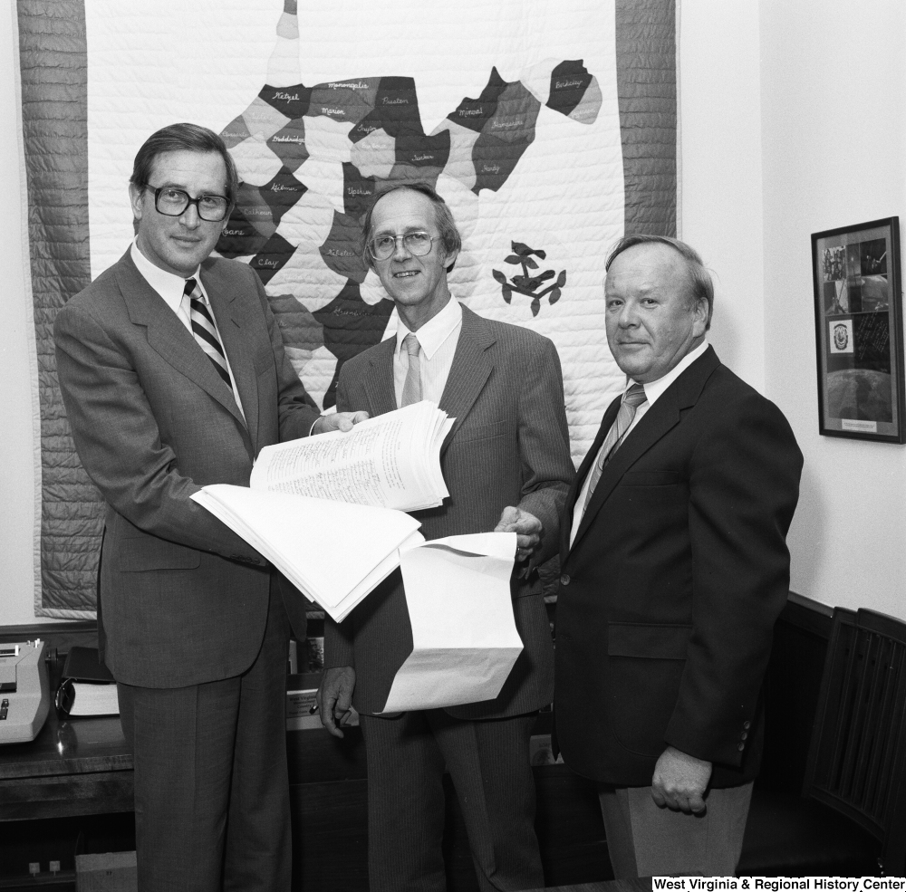 ["Senator John D. (Jay) Rockefeller holds a stack of papers and poses for a photograph with the County Commissioner from Marshall County, West Virginia."]%