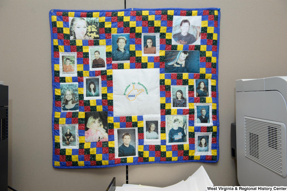 ["A quilt that reads \"Promise to Remember 2003\" hangs on a wall in Senator John D. (Jay) Rockefeller's office."]%