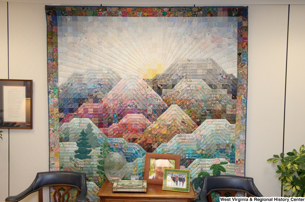 ["A colorful quilt hangs behind two chairs and a table in Senator John D. (Jay) Rockefeller's office."]%