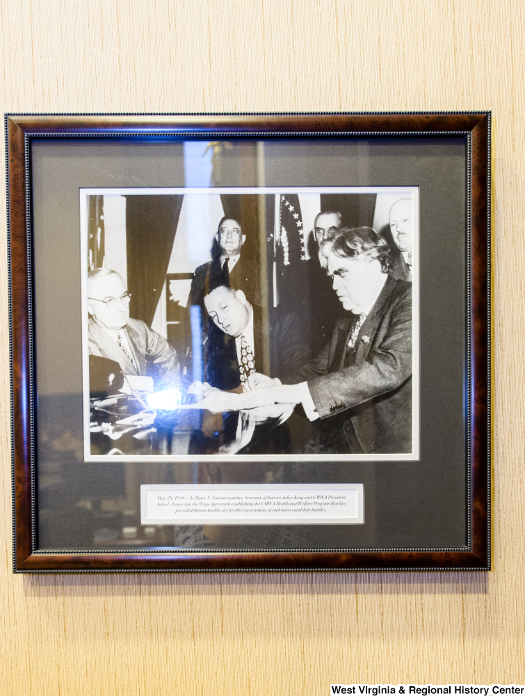 ["A photograph hangs on a wall in Senator Rockefeller's office that shows when the Secretary of the Interior and United Mine Workers of America President signing an agreement to provide lifetime health care for three generations of coal miners and their families."]%