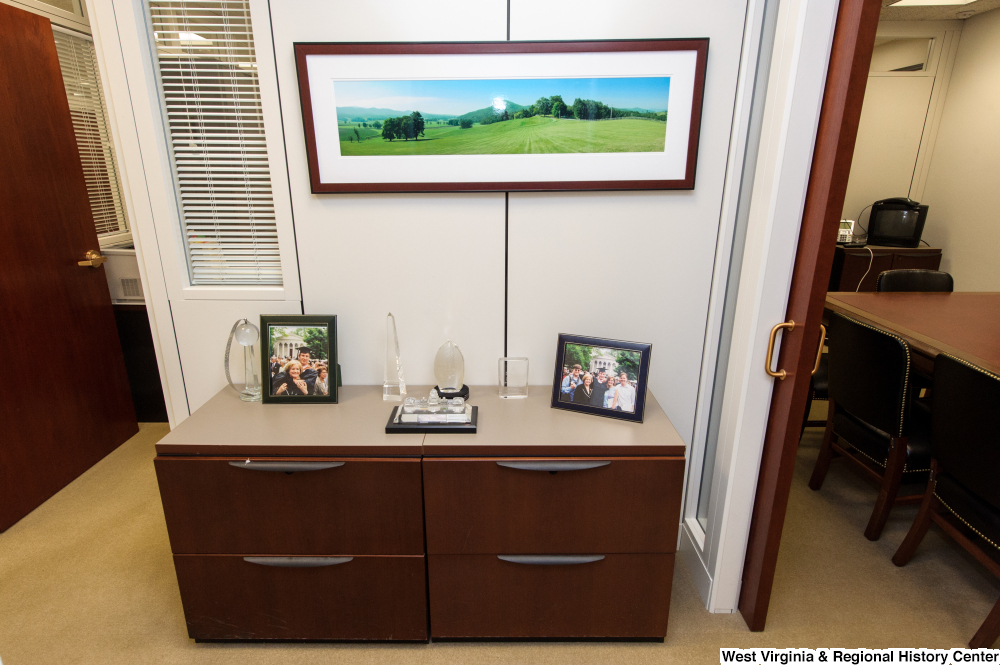 ["Crystal figures and Rockefeller family photos sit on some drawers in the Senator's office."]%