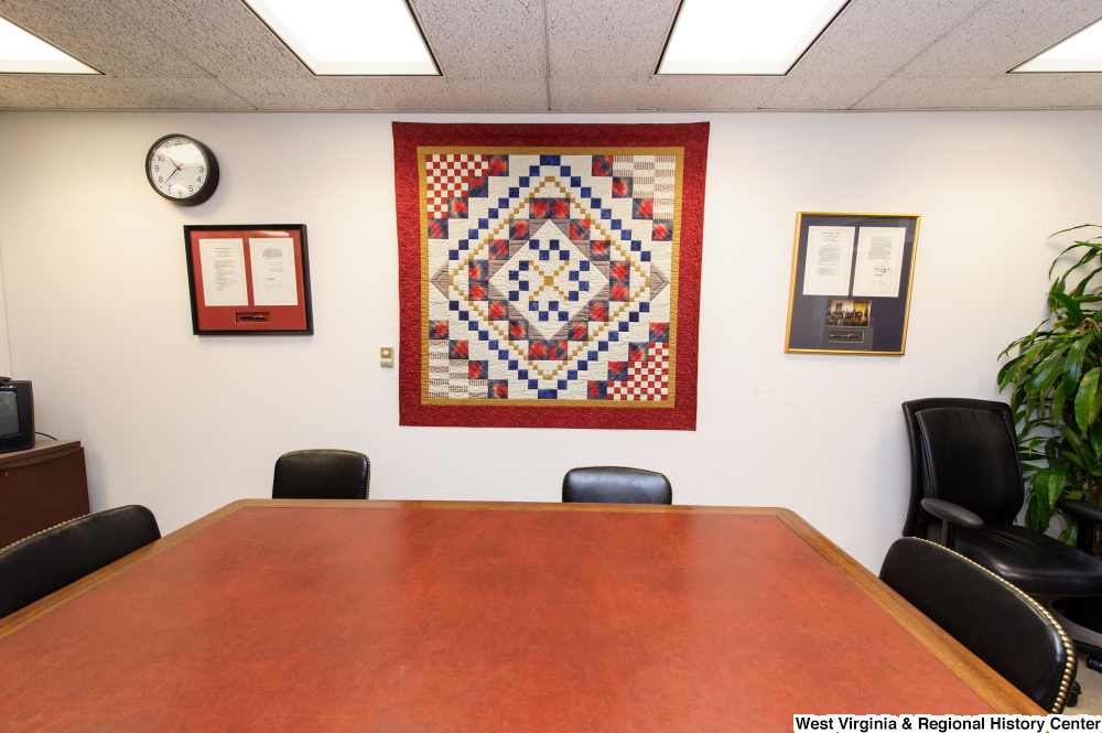 ["A quilt hangs on a wall behind a conference table in Senator John D. (Jay) Rockefeller's office."]%