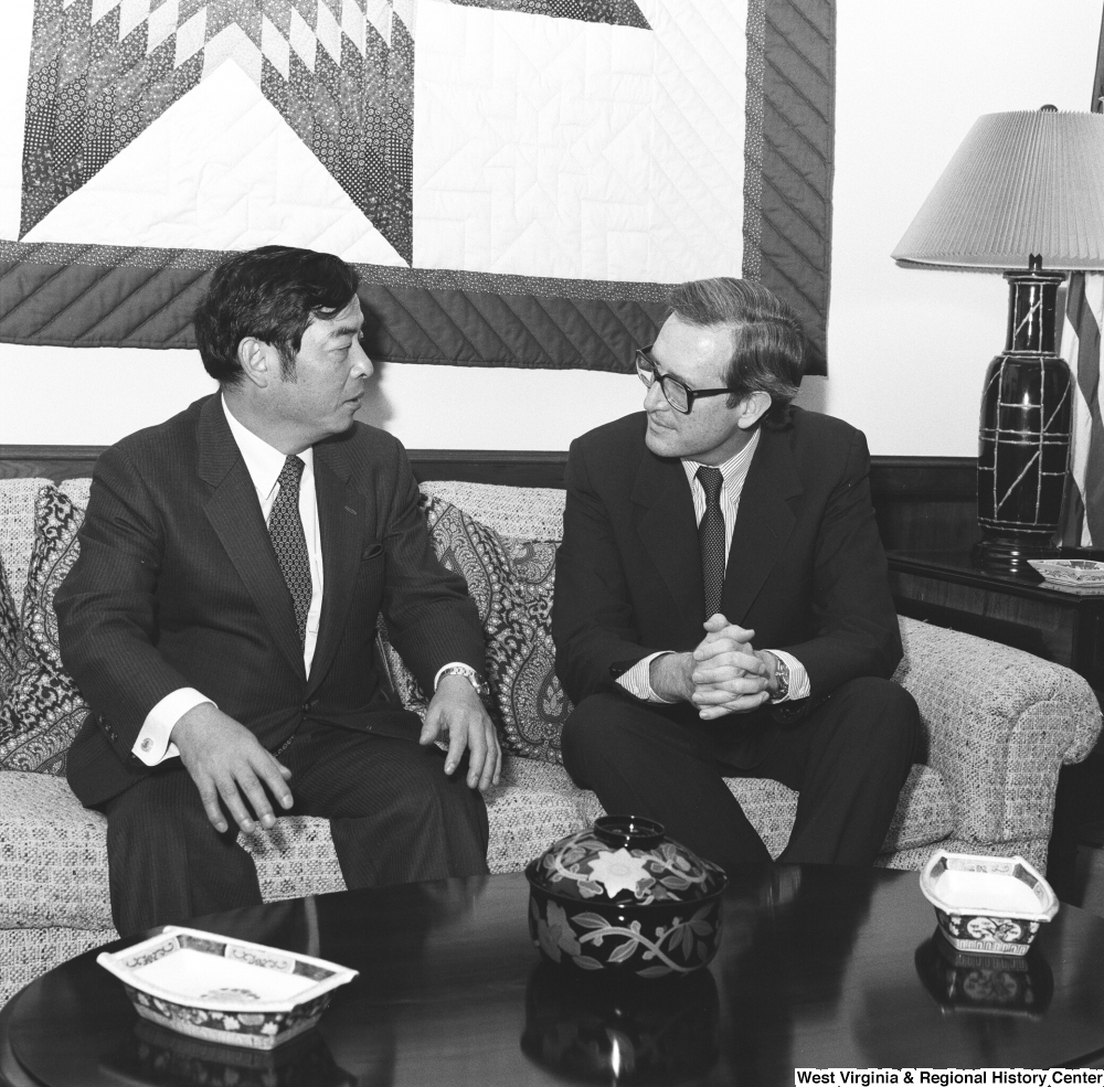 ["Senator John D. (Jay) Rockefeller sits on the couch in his office and speaks with an unidentified individual."]%