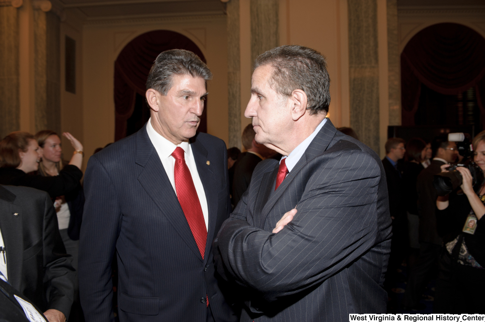 ["Senator Joe Manchin speaks with another man during his swearing-in ceremony."]%