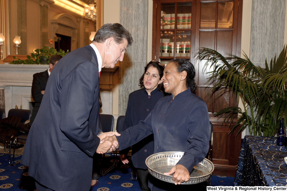 ["Senator Joe Manchin shakes hands with a US Capitol Building staff member after his swearing-in ceremony."]%