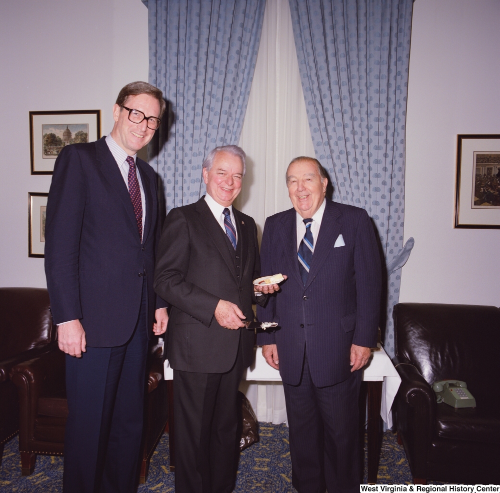 ["Senator Robert C. Byrd holds a piece of cake during his birthday celebration and stands for a photograph with Senator John D. (Jay) Rockefeller and former Senator Jennings Randolph."]%
